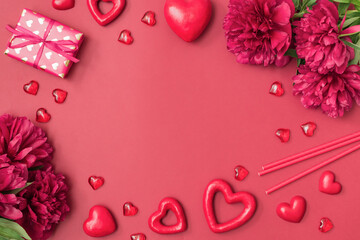 Wall Mural - Flat lay valentines day frame with red peonies, gift box and red hearts on a red background. Valentines day banner with copy space