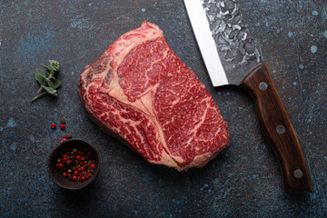 Canvas Print - Raw meat beef marbled prime cut steak Ribeye on rustic concrete kitchen table background from above with big knife and spices, beefsteak concept