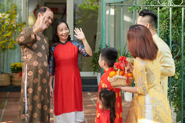 Poster - Happy grandparents greeting their children and grandchildren who came for Lunar New Year celebration at house entrance