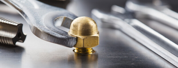 Wall Mural - Wrench tightens brass cap nut in steel billet. Spanner, bolt, screw and nuts.