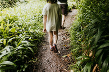Father And Daughter Walk Along A Muddy Path In Hawaiian Forest