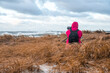 © Aerial Film Studio - Photographer sitting in the field taking photos of the stormy sea with huge waves