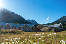 Refugio En Un Día Soleado Con Montañas De Fondo Desenfocadas Y Flores En El Cuadro En La Zona De Torres Del Paine. Patagonia Chilena 