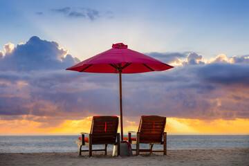 Fantastic romantic sunset, two sun beds, loungers, umbrella. White sand, sea view with horizon, colorful twilight sky, calm, relax seaside. Inspirational sea beach horizon couple vacation resort hotel