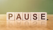 Wooden Blocks with the text: Pause on a green-brown background