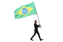 Full Length Profile Shot Of An Elegant Man In A Suit Walking And Carrying The Flag Of Brazil