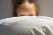 © Cavan Images - The girl covered herself with a pillow, only her eyes are open