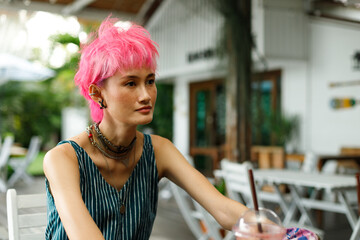 Wall Mural - Fashion Poses of Pink dying hair woman wear blue dress and sit in Tropical Cafe for soda drink Asian