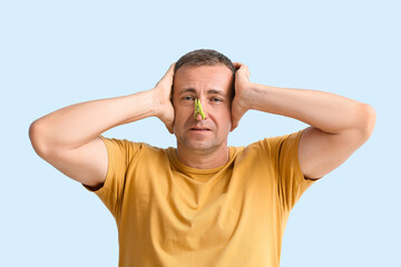 Sticker - Stressed ill mature man with clothespin on his nose against color background