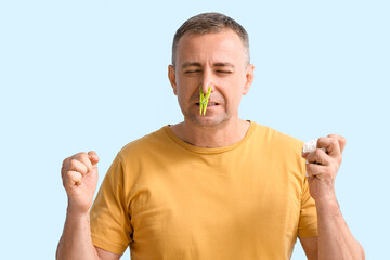 Sticker - Stressed ill mature man with clothespin on his nose against color background