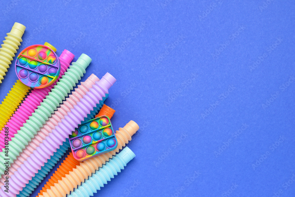 Colorful Pop Tubes and Pop it fidget toys on blue background
