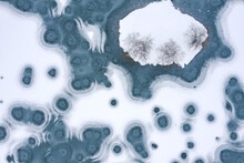 Aerial Top View Of A Frozen River, Covered By Thin Ice. Frosty Pattern On The River With Circles. Natural  Background.