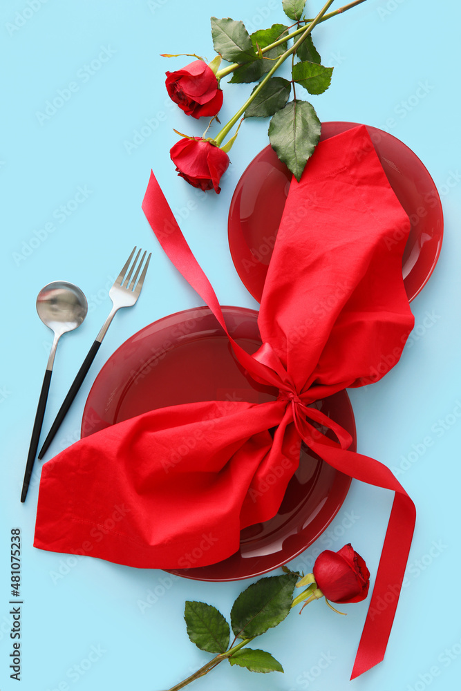 Beautiful table setting for Valentine's Day and rose flowers on blue background
