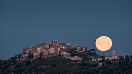 Wall Mural - Time lapse of moon setting behind the church of the ancient mountain village of Sant’Antonino in the Balagne region of Corsica