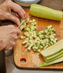 Canvas Print - Woman is cutting zucchini for cooking at home using recipe from the Internet