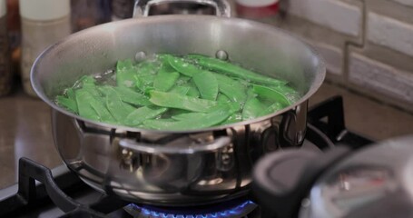 Canvas Print - Green peas are cooked in saucepan on the gas stove