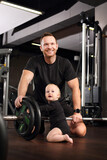 Fototapeta  - Training with a child. Dad and baby at the gym
