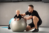 Fototapeta Londyn - Physiotherapy and rehabilitation of a child. Physiotherapist exercises with a baby on a ball.