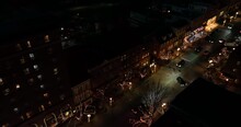Small Town Decorated For Christmas. Lights At Night. Aerial Tracking Shot Of Cars Driving In City.