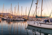 Pier With Motorboats And Yachts Moored Alongside At Sunset