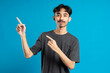 © Duck Stock - man with beaming smile on blue background is pointing on empty copy space with his fingers