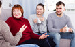 © JackF - Smiling mature lady with adult children enjoying conversation with female friend at home