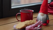 Holidays, Decoration And Celebration Concept - Christmas Gnome, Cup Of Coffee In Red Mug, Ginger Cookies And Candy Canes On Window Sill At Home