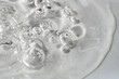Transparent facial serum with bubbles on light grey background macro. Liquid bubbly gel with hyaluronic acid closeup. Moisturising cosmetic product texture. Skin care beauty routine. 