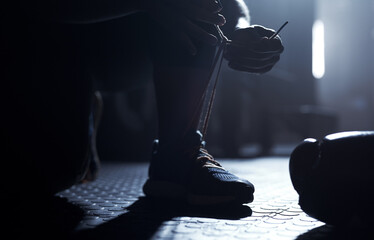 Wall Mural - Step up your game. Closeup shot of an unrecognisable man tying his laces in a gym.