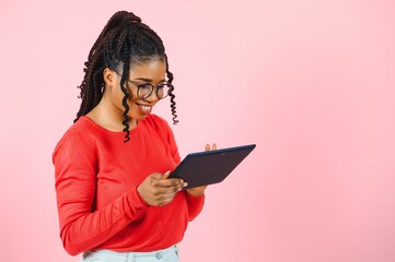 Cool gadget. Interested girl using digital tablet on pink background