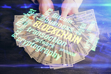 Multi exposure of blockchain theme drawing hologram and USA dollars bills and man hands. Business concept.