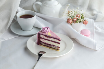 Wall Mural - Homemade purple cake with souffle cream and blueberry and cup of tea on the table