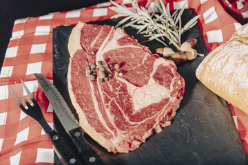 Raw beef filet mignon steaks with rosemary, pepper and salt on dark rustic board, black angus meat.