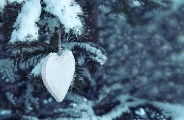 Wall Mural - wood heart on snow covered pine branch .valentines day background.