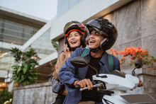 An Asian Man And Woman Wearing Helmet Riding A Motorcycle