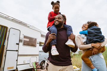 Wall Mural - Black parents laughing while playing with their children by trailer