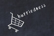 Chalk drawing of shopping cart and word hurriedness on black chalboard. Concept of globalization and mass consuming