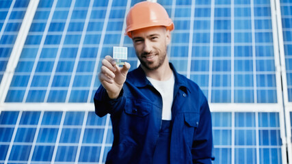 smiling engineer showing small model of solar panel