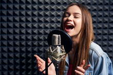 Teen Girl In Recording Studio With Mic Over Acoustic Absorber Panel Background