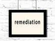 Black frame hanging on white brick wall with inscription remediation