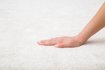 Young adult woman hand touching white new fluffy carpet surface. Closeup. Checking softness. Side view.