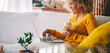 © simona - Side view of young adult woman have relax leisure at home using laptop and drinking. MOdern female people with computer sitting on the sofa. Smiling lady enjoy connection technology indoor