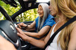 © Drobot Dean - Multiracial women smiling and using cellphone while driving car