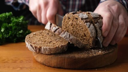 Canvas Print - Slicing whole grain rye bread on wooden board, closeup view. Freshly baked bread