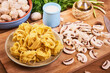Ingredients for cooking pasta with mushroom sauce - chopped champignons, fettuccine pasta, cream in a jug