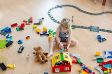 Cute Child, Playing With Colorful Toy Blocks. Little Boy Building House Of Block Toys Sitting On The Floor In Sunny Spacious Bedroom