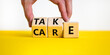 Take care symbol. Businessman turns wooden cubes and changes the word take to care. Beautiful yellow table, white background, copy space. Business and take care concept.