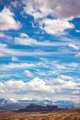 Wall Mural - A blue cloudy sky over a diverse landscape with various biomes in Arches National Park in Utah.
