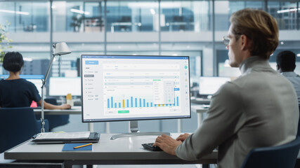 Close Up Over the Shoulder Shot of a Businessman Working on Desktop Computer with Finance Statistical Data Software. Digital Projects Manager Typing Data, Using Keyboard and Mouse.