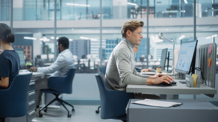 Leinwandbilder - In Big Corporate Office: Portrait of Confident Handsome Manager in Grey Turtleneck Using Computer, Businesspeople and Experts Working Around Him, Analysing Statistics, Commerce Data, Marketing Plans.